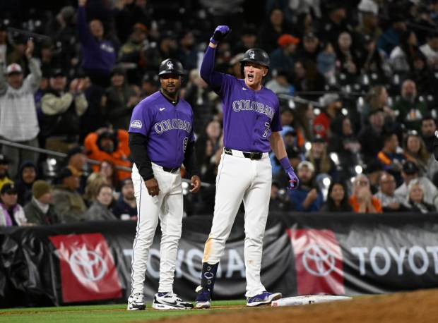 Colorado Rockies' TJ Rumfield, right, cheers next to third base coach Andy González, left, after hitting a two-run triple in the fifth inning of a baseball game against the Houston Astros, Monday, April 6, 2026, in Denver. (AP Photo/Geneva Heffernan)