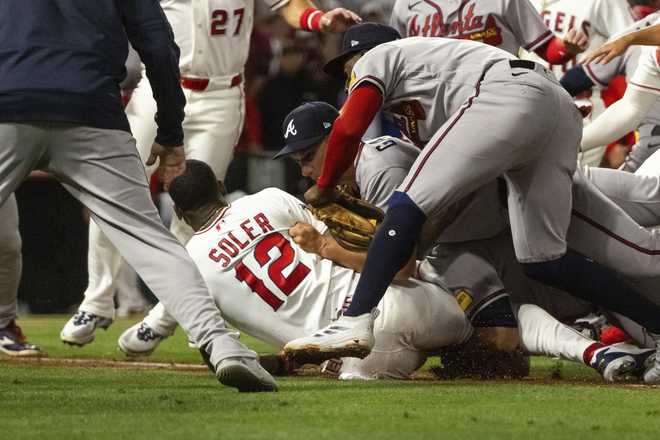 Los Angeles Angels' Jorge Soler (12) is tackled to the ground by Atlanta Braves players as a fight breaks out during the fifth inning of a baseball game, Tuesday, April 7, 2026, in Anaheim, Calif.