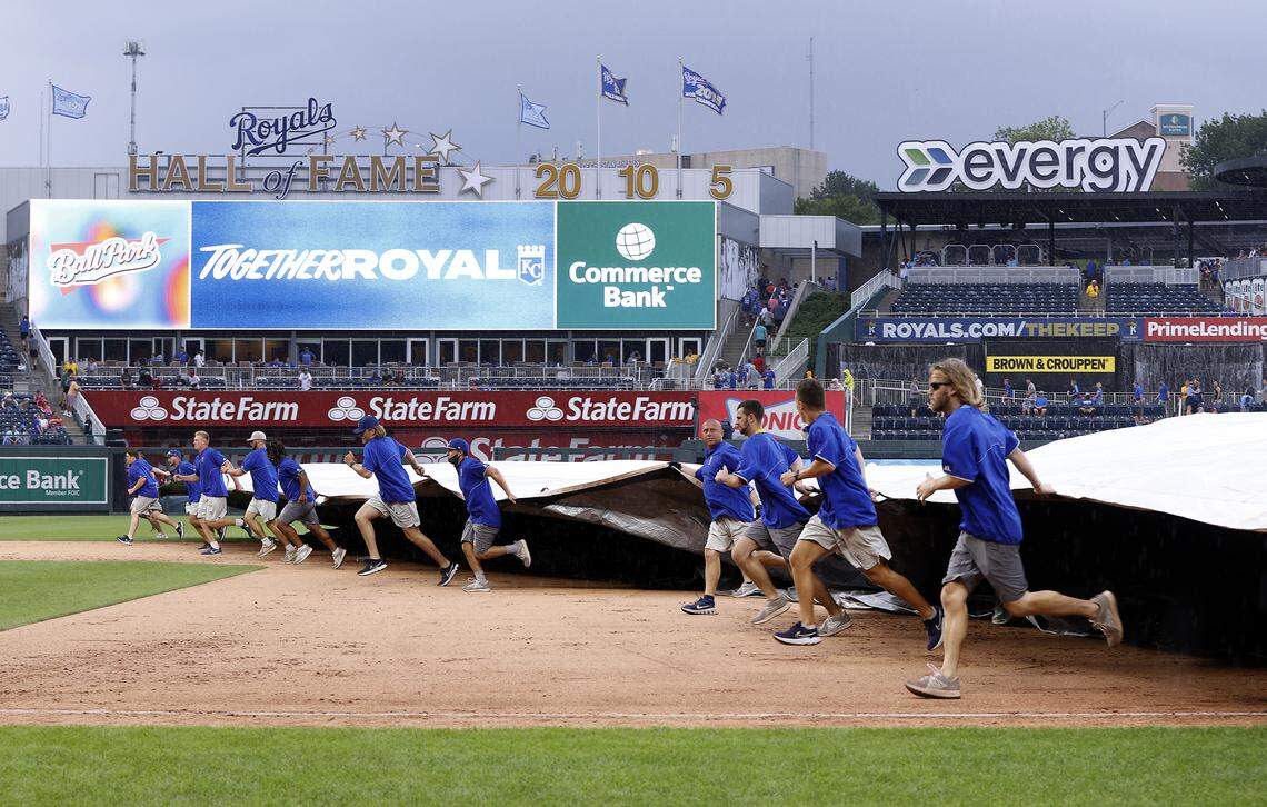 Kansas City Royals grounds crew members cover the field during a rain delay in the seventh inning of the game against the Cincinnati Reds at Kauffman Stadium on July 07, 2021 in Kansas City, Missouri.