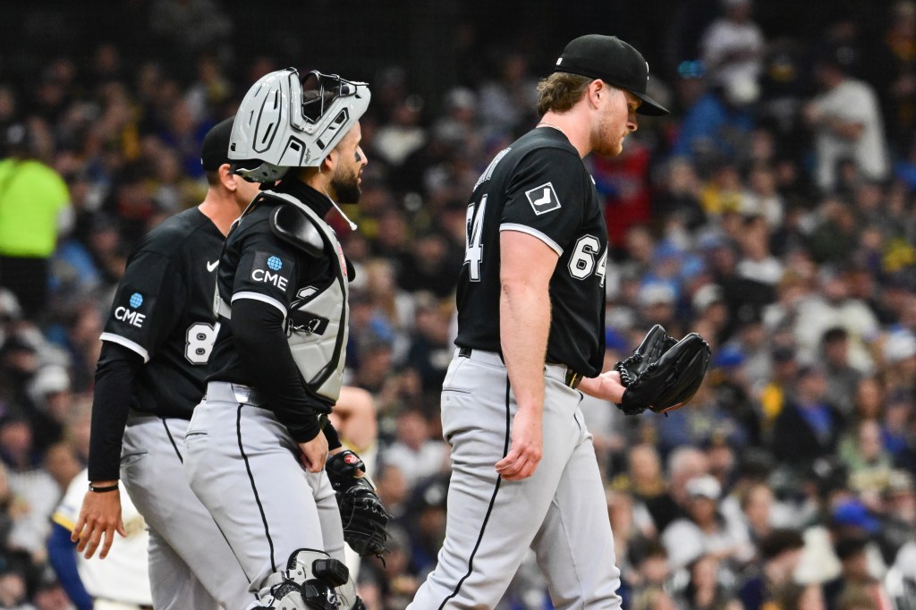 Chicago White Sox pitcher Shane Smith (64) walks off the field with a catcher and coach.