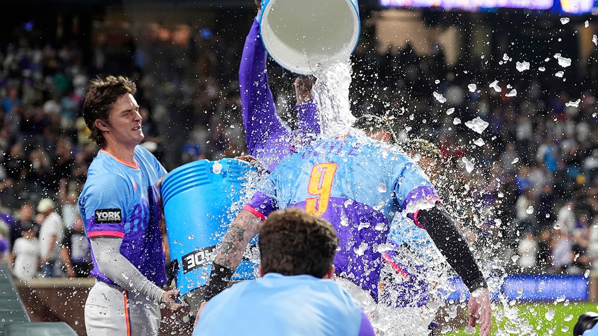 Brenton Doyle being doused by Mickey Moniak and Orlando Arcia after hitting a walkoff home run