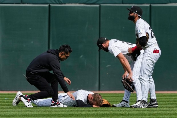 Chicago White Sox left fielder Tanner Murray is checked by a team trainer after being injured during the 10th inning of a game against the Washington Nationals in Chicago, Sunday, April 26, 2026. (AP Photo/Nam Y. Huh)