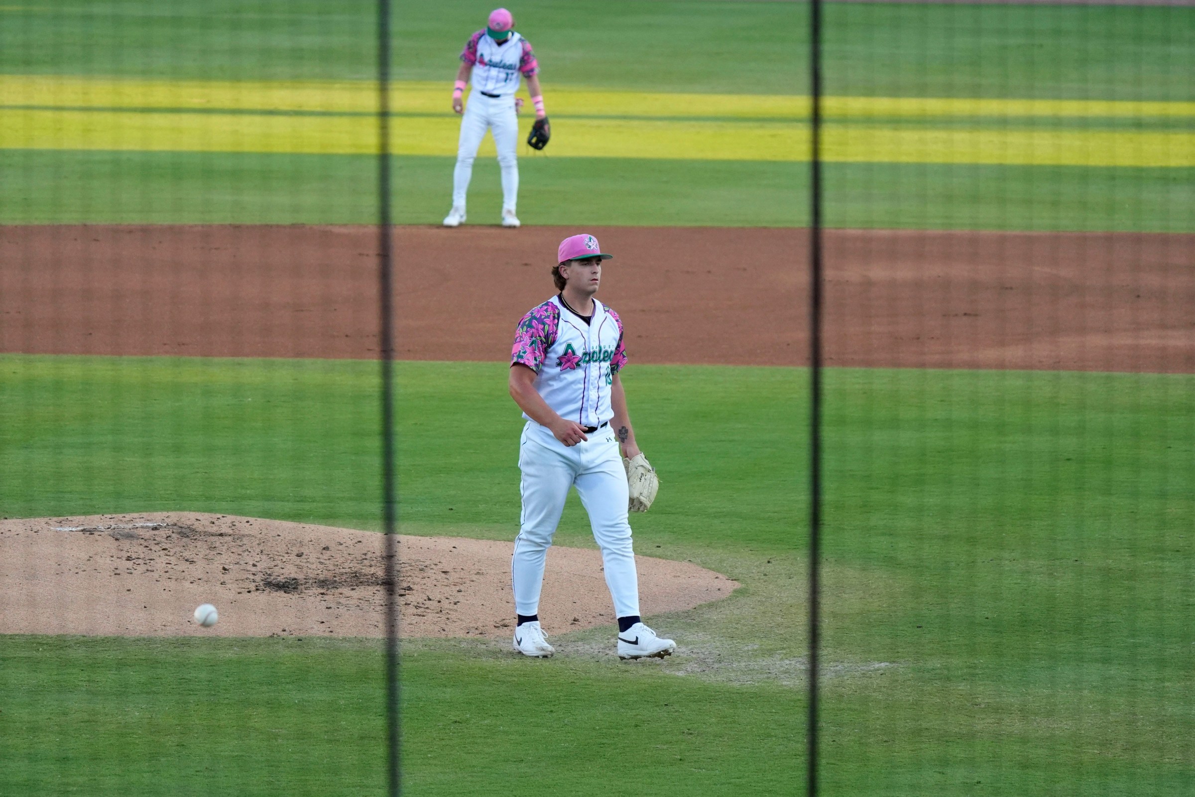 Apr 18, 2025; North Augusta, South Carolina, USA; Augusta GreenJackets Ethan Bagwell (18) is seen between the nets during the Augusta GreenJackets and Myrtle Beach baseball game at SRP Park. The Augusta GreenJackets unveiled their new Augusta Azalea uniforms. Mandatory Credit: Katie Goodale - Augusta Chronicle/USA TODAY NETWORK