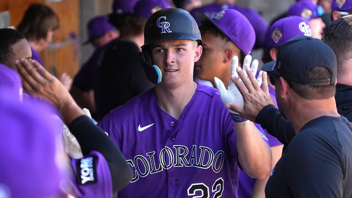 Colorado Rockies right fielder Mickey Moniak celebrating with teammates on the field.