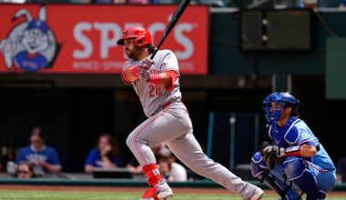 Cincinnati Reds' Eugenio Suarez (28) follows through on a run-scoring single as Texas Rangers' Kyle Higashioka (11) looks on in the fourth inning of a baseball game Sunday, April 5, 2026, in Arlington, Texas. (AP Photo/Tony Gutierrez)
