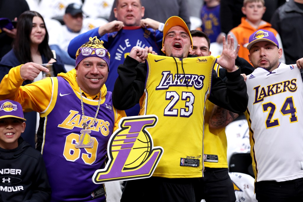 Fans in Lakers jerseys at a basketball game.
