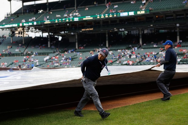 Members of the grounds crew cover the field with a rain tarp before the Cubs play the Reds on Monday, May 4, 2026, at Wrigley Field. (Armando L. Sanchez/Chicago Tribune)