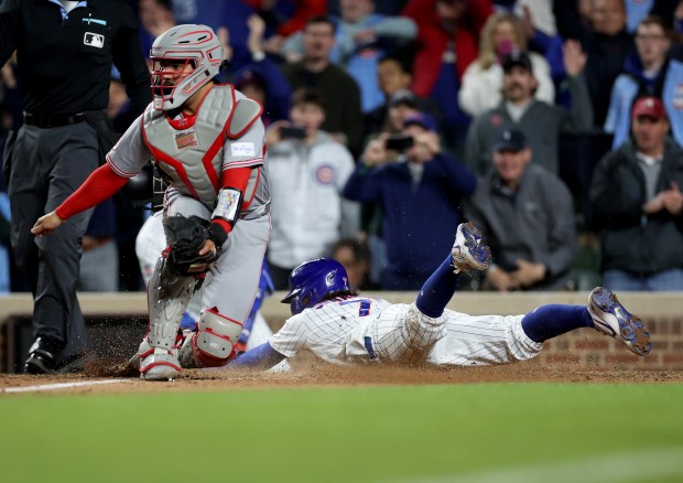 Chicago Cubs shortstop Dansby Swanson (7) slides in safely at home to score the game-winning run on a single by teammate Michael Busch in the tenth inning of a game against the Cincinnati Reds at Wrigley Field in Chicago on May 5, 2026. (Chris Sweda/Chicago Tribune)