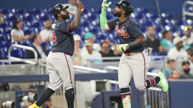 Atlanta Braves' Michael Harris II, right, high-fives third base coach...