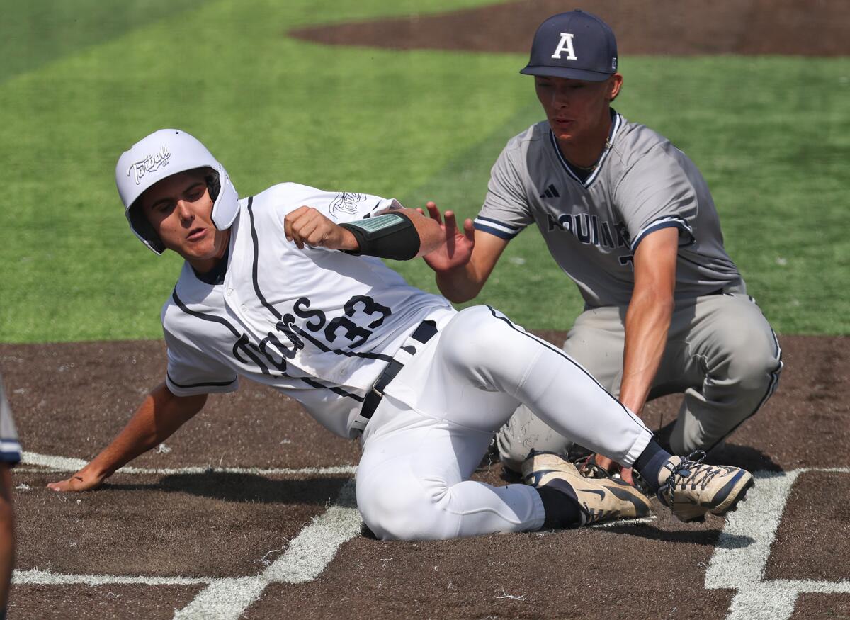 Newport Harbor's Cameron Hatfield (33) slides into home for a run against San Bernardino Aquinas on Friday.