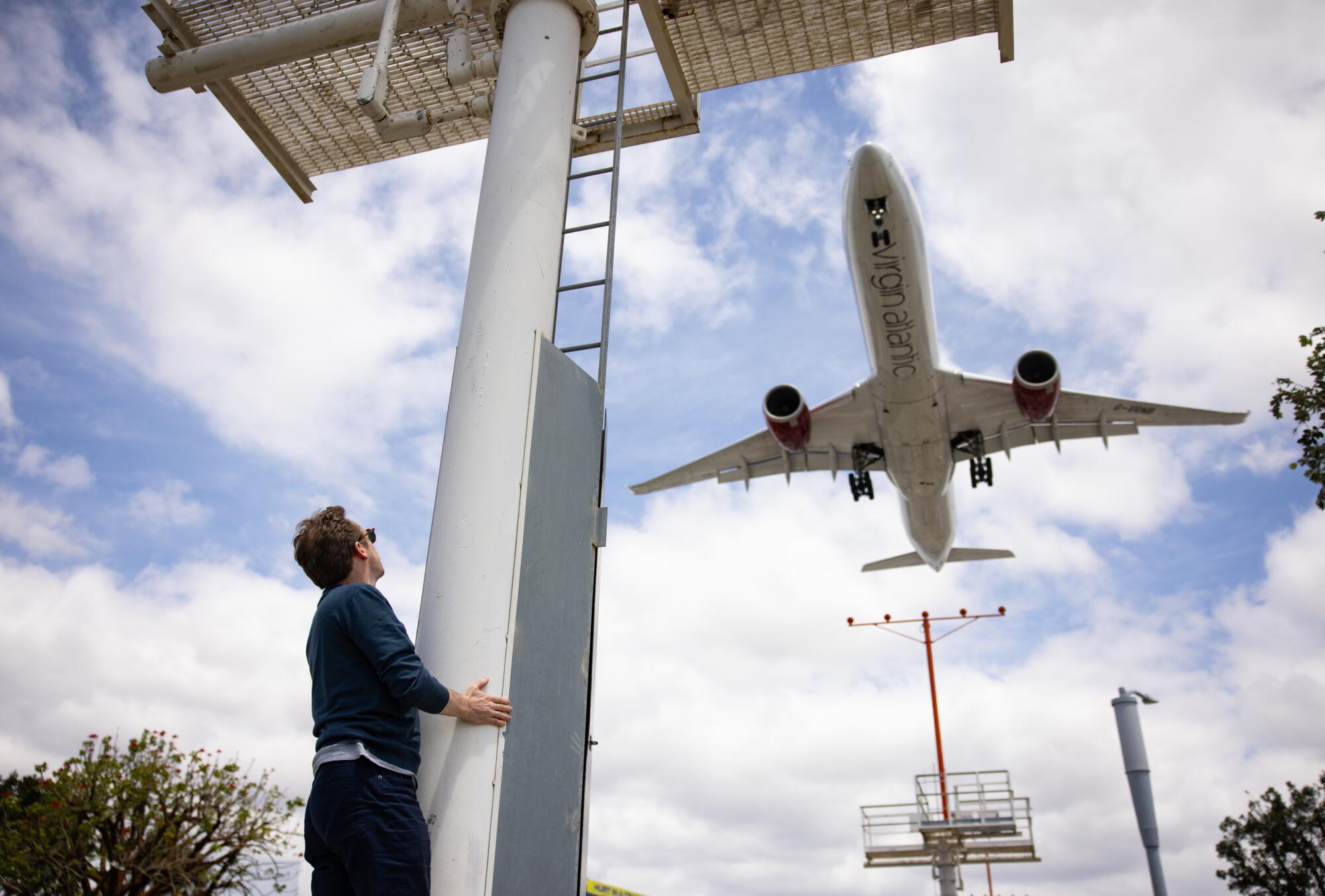 Daniel Harding looks at a plane flying by outside the In-N-Out Burger.