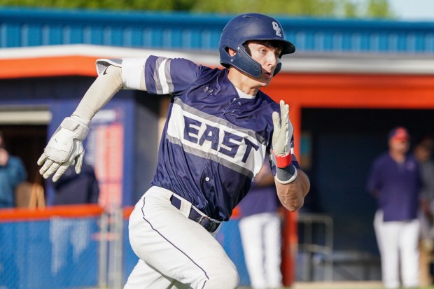Oswego East's Dominic Battista (14) runs out a single driving in a run against Oswego during a Southwest Prairie Conference game in Oswego on Monday, May 11, 2026. (Sean King / For The Beacon-News)