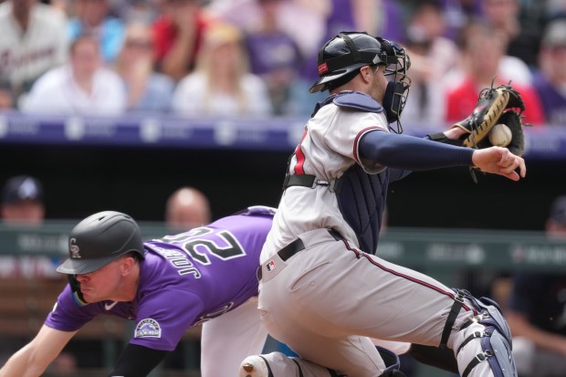 Atlanta Braves catcher Jonah Heim,right, fields a throw as Colorado Rockies' Troy Johnston, left, scores on a sacrifice fly hit by Rockies' Ezequiel Tovar in the fifth inning of a baseball game Sunday, May 3, 2026, in Denver. (AP Photo/David Zalubowski)