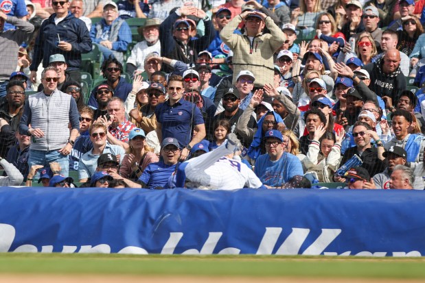 Fans react after Chicago Cubs first baseman Michael Busch (29) dives over the rain tarp as he tried to catch a foul ball in the ninth inning against the Arizona Diamondbacks at Wrigley Field on May 3, 2026. (Eileen T. Meslar/Chicago Tribune)