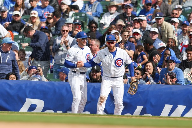 Chicago Cubs second baseman Nico Hoerner (2) helps first baseman Michael Busch (29) up after Busch fell over the rain tarp trying to catch a foul ball in the ninth inning against the Arizona Diamondbacks at Wrigley Field on May 3, 2026. (Eileen T. Meslar/Chicago Tribune)