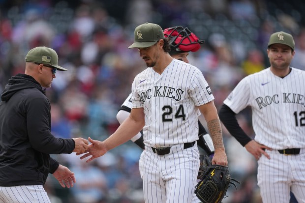 Colorado Rockies manager Warren Schaeffer, left, takes the ball from starting pitcher Michael Lorenzen (24) who is pulled from the mound while third baseman Kyle Karros, right, looks on in the fifth inning of a baseball game against the Arizona Diamondbacks, Sunday, May 17, 2026, in Denver. (AP Photo/David Zalubowski)
