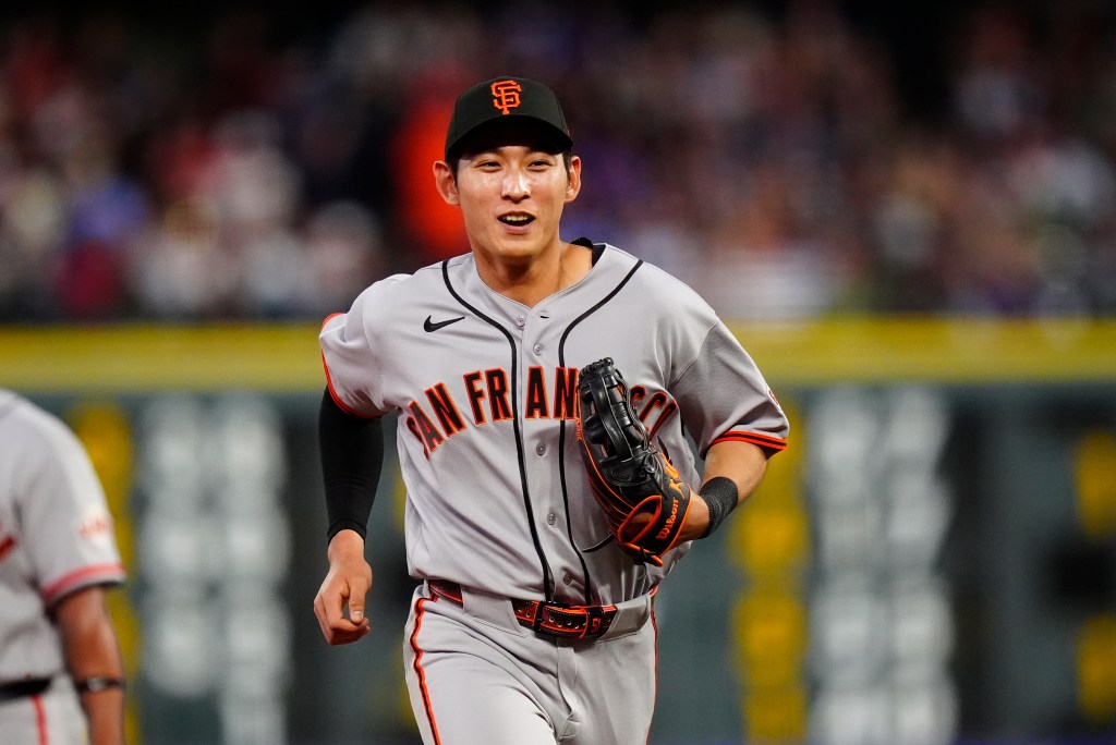 A San Francisco Giants player in a grey uniform, black cap, and black glove runs on the baseball field.