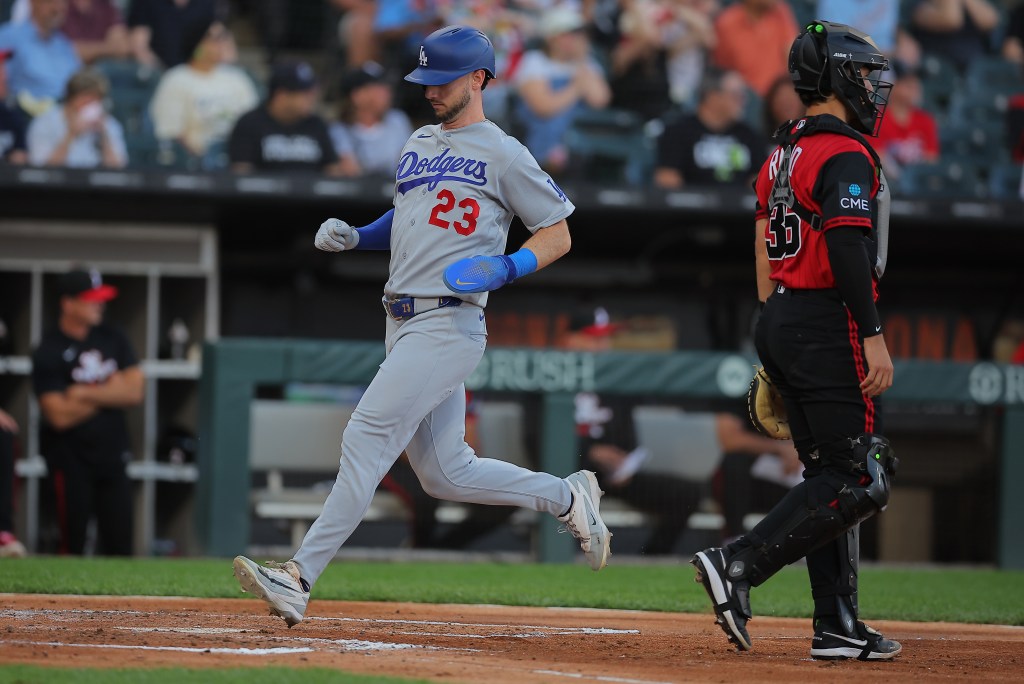 Kyle Tucker wearing a grey Dodgers jersey with the number 23 runs past a catcher in a red and black uniform.