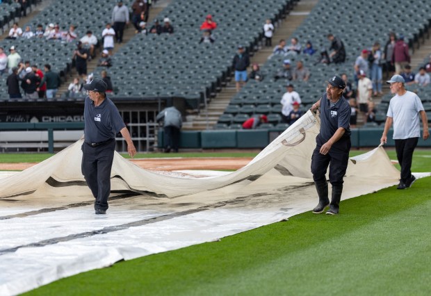 Grounds-crew members fold the tarp covering the field during a rain delay ahead of a Chicago White Sox-Cleveland Guardians game Wednesday, June 24, 2026, at Rate Field. (Josh Boland/Chicago Tribune)