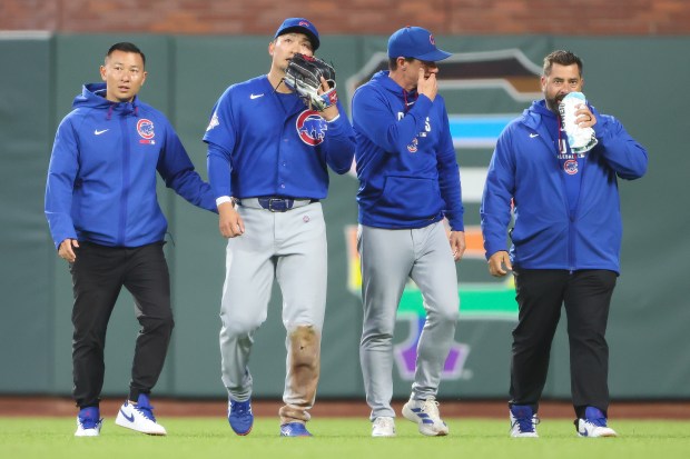Cubs right fielder Seiya Suzuki, second from left, walks off the field with his interpreter, left, manager Craig Counsell, second from right, and a trainer, right, after being injured while attempting to catch a fly ball during the fourth inning against the Giants on Saturday, June 13, 2026, in San Francisco. (Scott Marshall/AP)