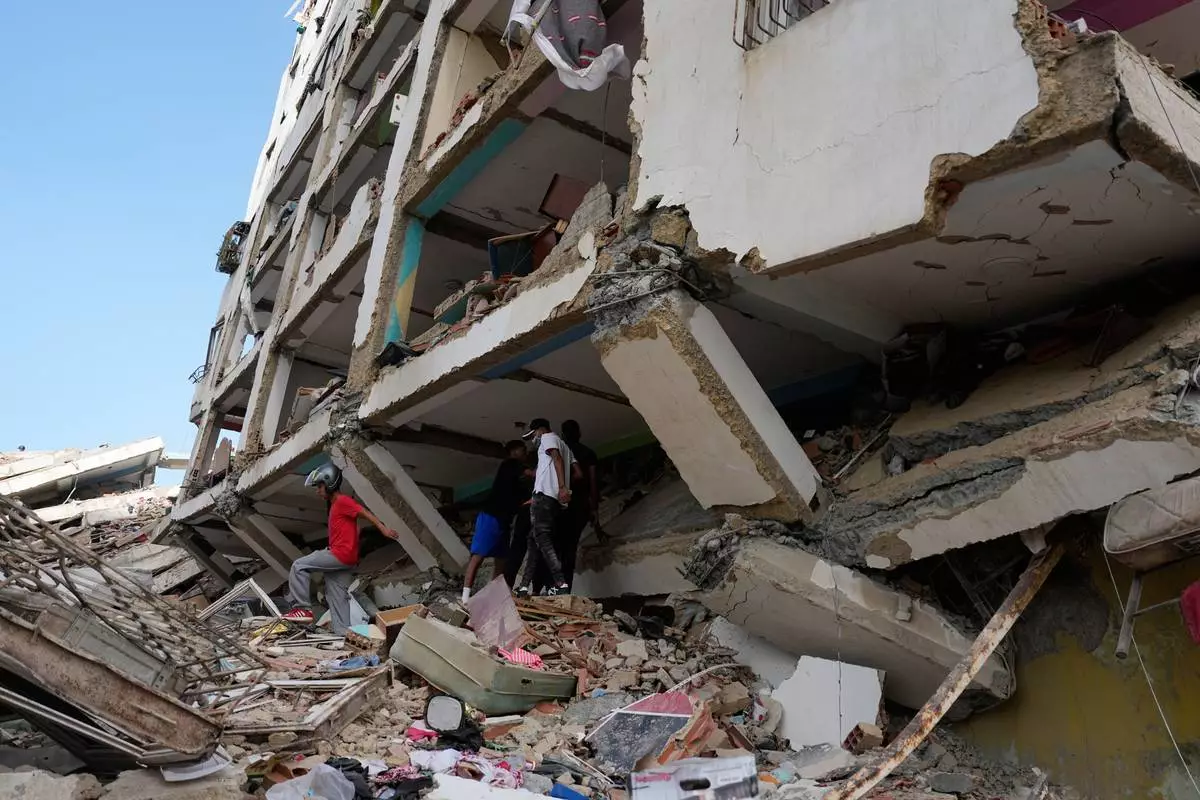 Residents walks through the rubble two days after earthquakes struck Catia La Mar, Venezuela, Friday, June 26, 2026. (AP Photo/Fernando Vergara)