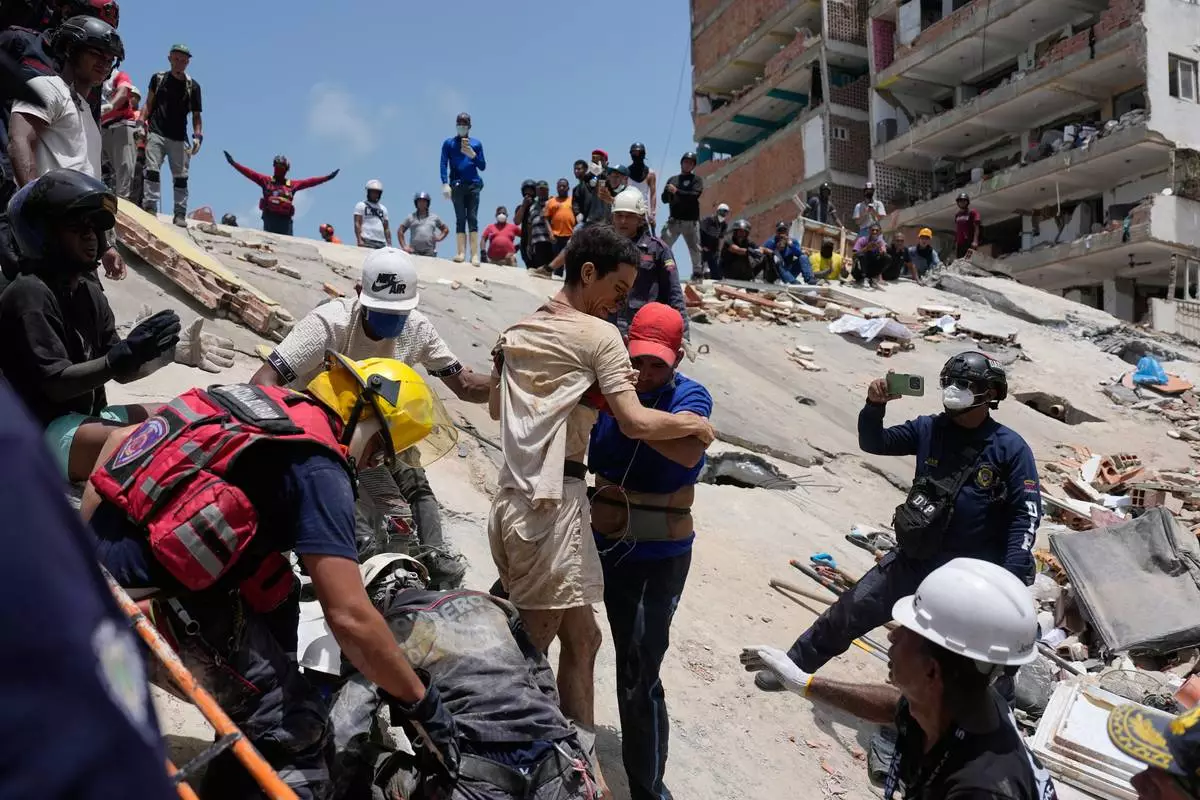 Rescue workers aid Daniel Cordero after pulling him from the rubble two days after an earthquake struck Catia la Mar, Venezuela, Friday, June 26, 2026. (AP Photo/Fernando Vergara)