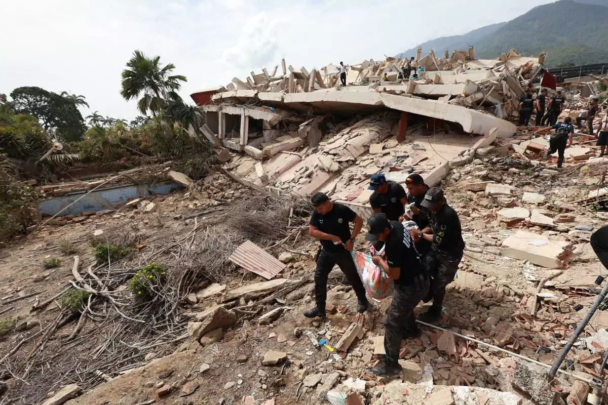 Police carry a body recovered from the rubble of a building in La Guaira, Venezuela, Thursday, June 25, 2026, a day after successive powerful earthquakes struck the country. (AP Photo/Javier Campos)