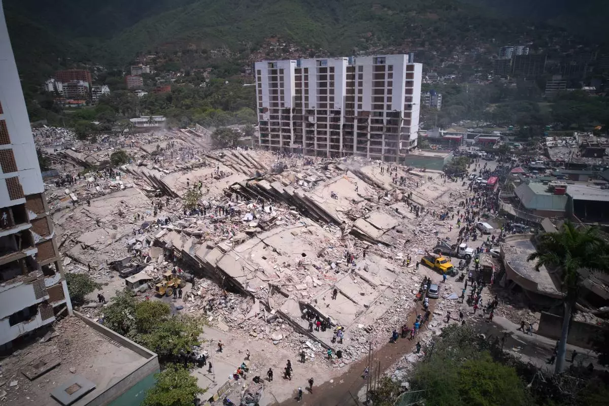 Residents and rescue workers search through the rubble two days after an earthquake struck La Guaira, Venezuela, Friday, June 26, 2026. (AP Photo/Juan Pablo Arraez)