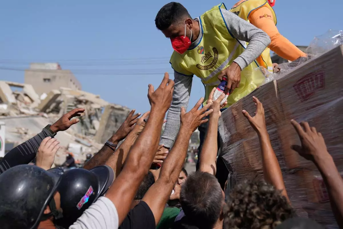 Members of a religious organization distribute food to people affected two days after an earthquake struck La Guaira, Venezuela, Friday, June 26, 2026. (AP Photo/Ariana Cubillos)