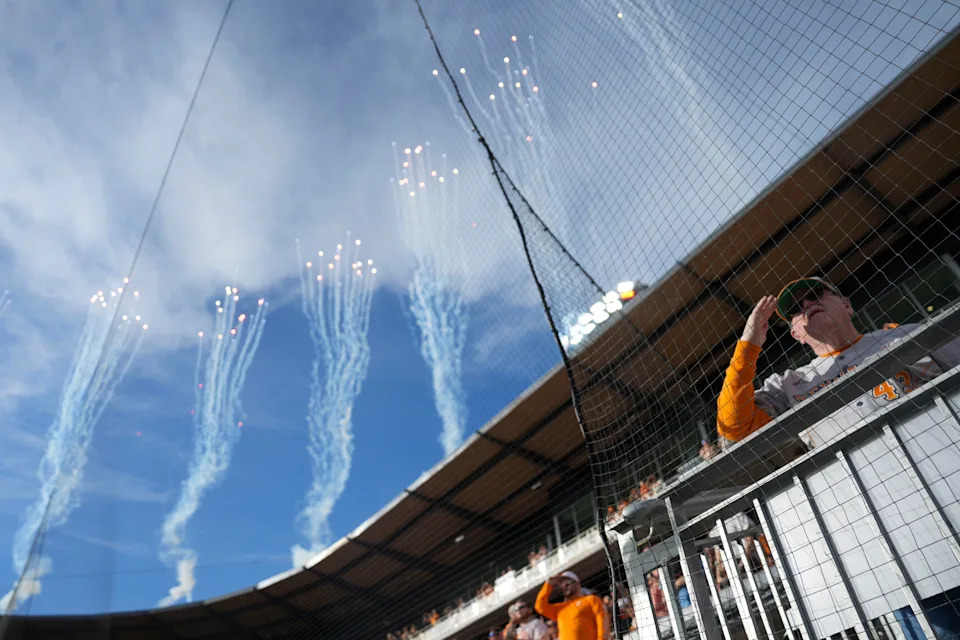 A Tennessee fan salutes during the singing of the national anthem while fireworks shoot from Lindsey Nelson Stadium at the start of the NCAA college baseball game between the Tennessee Volunteers and Texas Longhorns in Knoxville, Tennessee on May 8, 2026.