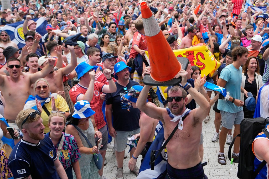 A Scotland soccer fan dances with a traffic cone on his head during a march.