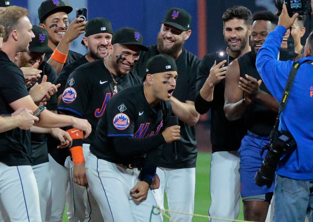 New York Mets second baseman Jose Iglesias #11, singing his hit song, "OMG," on the field surrounded by his teammates