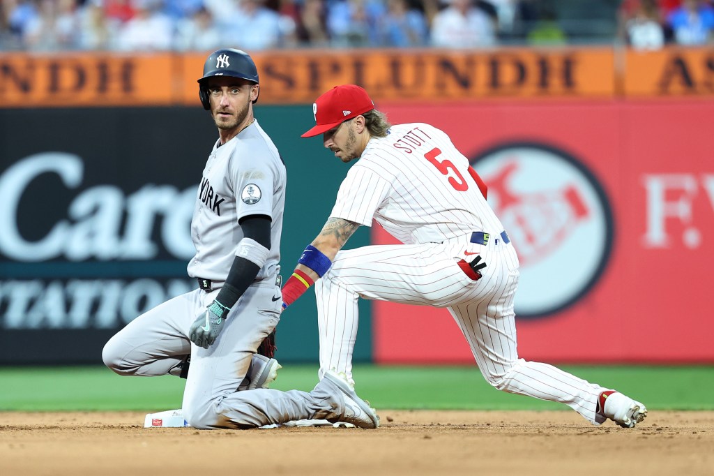 Cody Bellinger of the New York Yankees sliding into second base while Bryson Stott of the Philadelphia Phillies kneels nearby.
