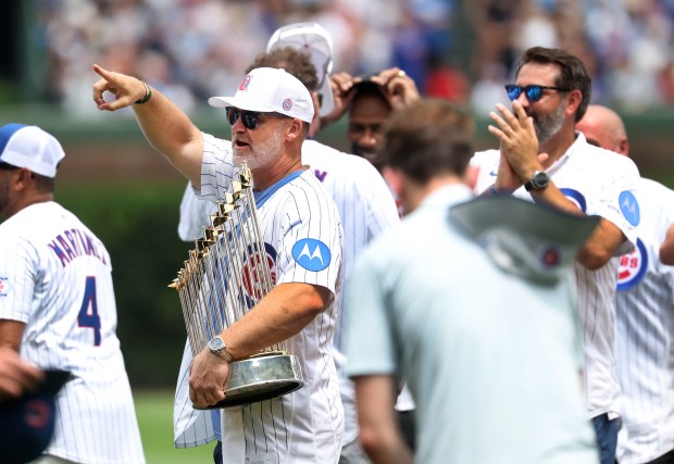 Former Cubs catcher and manager David Ross holds the World Series trophy while standing beside his former teammates on the field as the 2016 World Series champion team is honored before a game against the Twins on July 18, 2026, at Wrigley Field. (Chris Sweda/Chicago Tribune)