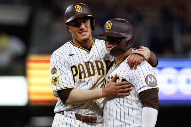 Manny Machado #13 and Ty France #25 of the San Diego Padres hug during the seventh inning against the Colorado Rockies at Petco Park on Tuesday, July 28, 2026 in San Diego, California. (Meg McLaughlin / The San Diego Union-Tribune)