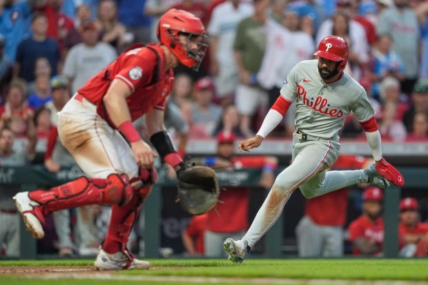 The Philadelphia Phillies' Derek Hill runs toward home plate to score on a single by Justin Crawford as Cincinnati Reds catcher Tyler Stephenson awaits the throw during the eighth inning in Cincinnati on Thursday, July 9, 2026. (AP Photo/Carolyn Kaster)