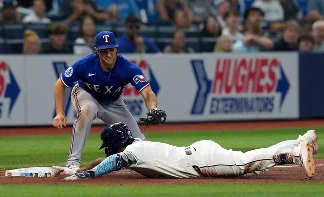 Tampa Bay Rays' Junior Caminero slides into third base with a triple ahead of the tag by Texas Rangers' Josh Smith during the sixth inning of a baseball game Tuesday, July 28, 2026, in St. Petersburg, Fla. (AP Photo/Chris O'Meara)
