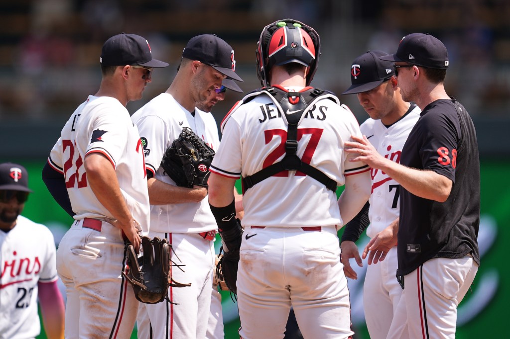 Minnesota Twins pitcher Taylor Rogers, pitching coach Pete Maki, and teammates during a baseball game.