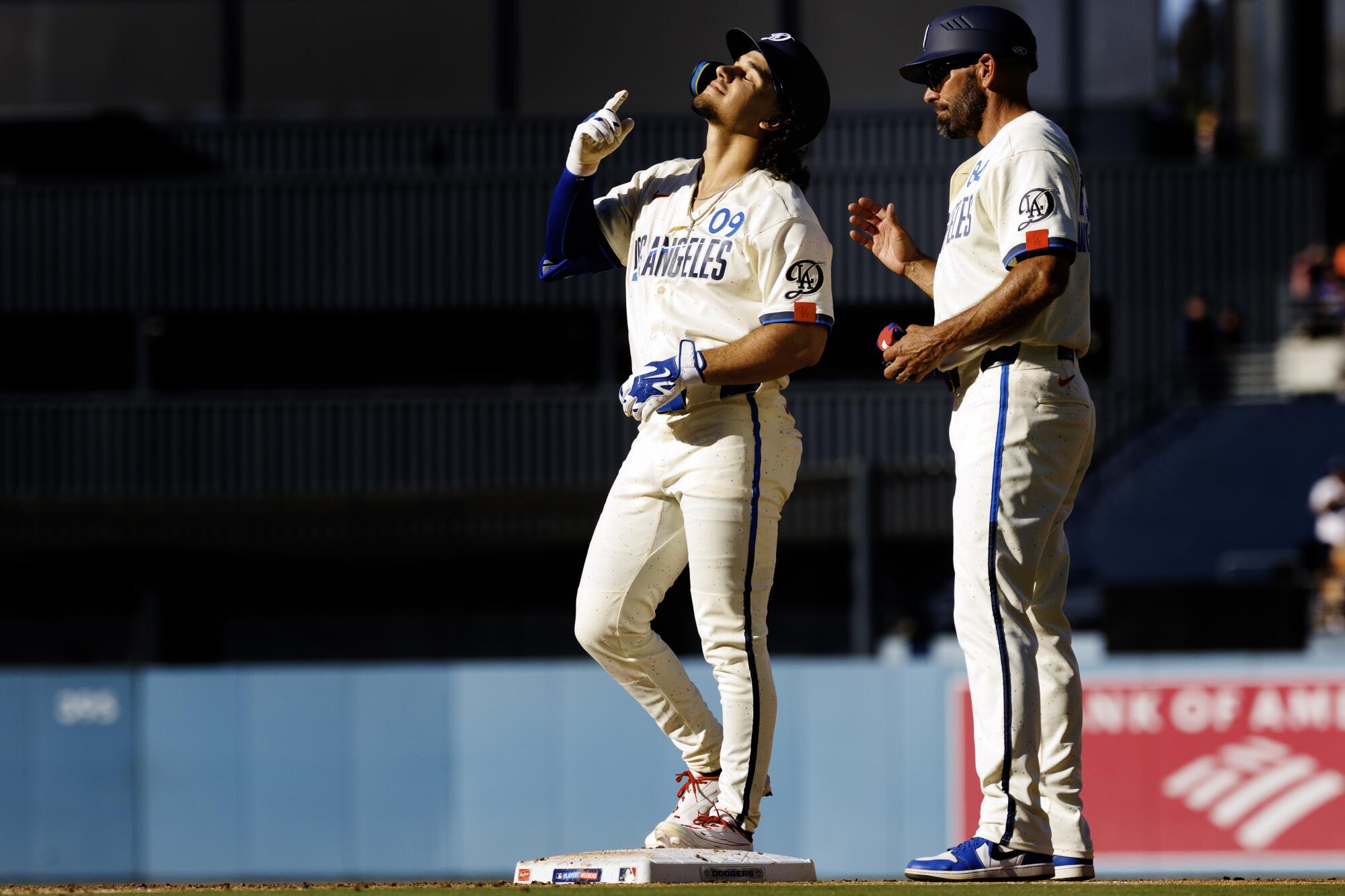 Dodgers center fielder Alek Thomas points skyward next to first base coach Chris Woodward.
