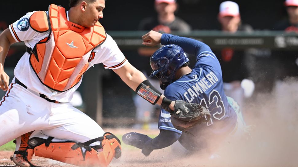 Tampa Bay Rays' Junior Caminero (13) slides into home plate to score as Baltimore Orioles catcher Samuel Basallo, left, tags in the sixth inning of a baseball game Sunday, Aug. 23, 2026, in Baltimore. (AP Photo/Gail Burton)