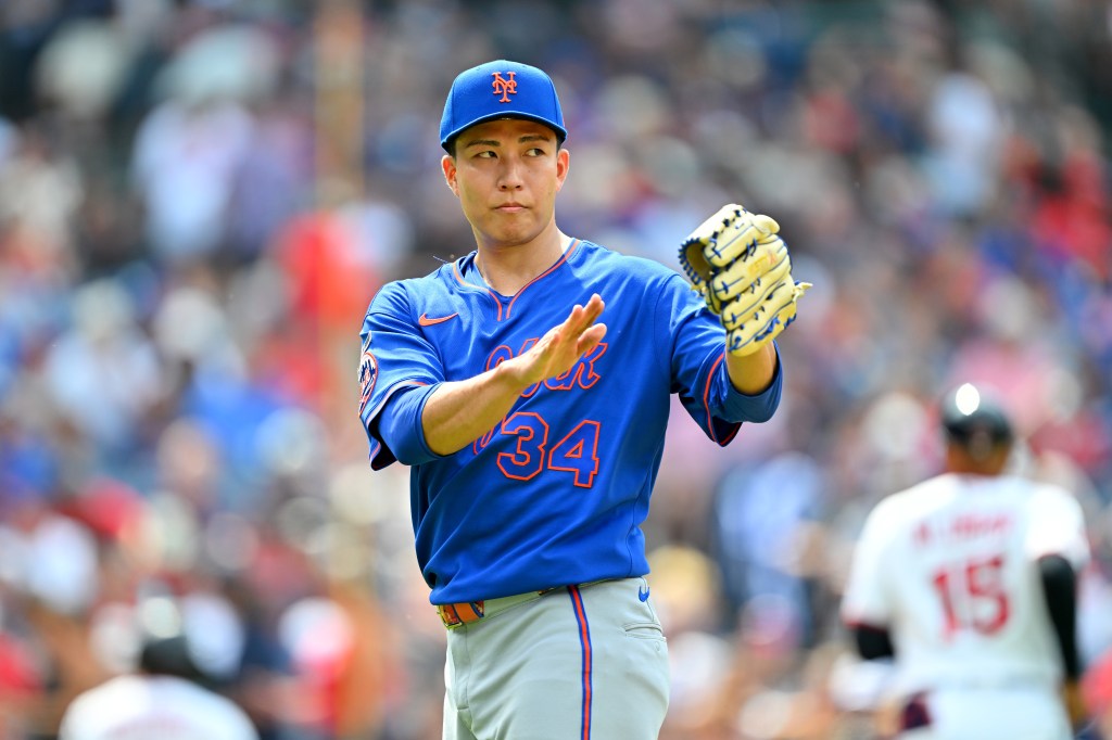 A baseball player in a blue Mets uniform with the number 34 and a blue cap holds his glove up.