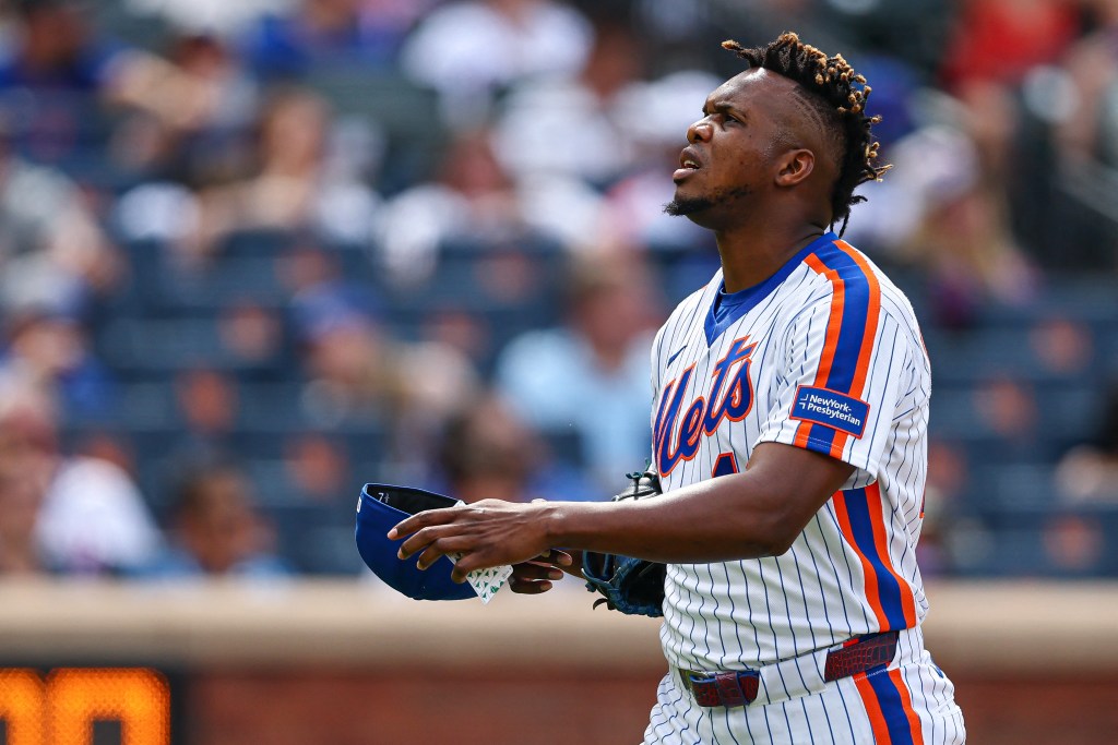 New York Mets pitcher Huascar Brazoban walks off the field holding his cap.