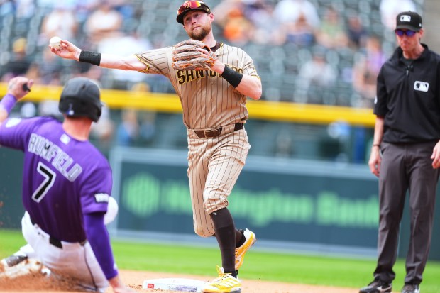 San Diego Padres second baseman Jake Cronenworth, back, throws over Colorado Rockies' TJ Rumfield after forcing him out at second base on the front end of a double play hit into by Kyle Karros to end the fourth inning of a baseball game Thursday, Sept. 17, 2026, in Denver. (AP Photo/David Zalubowski)