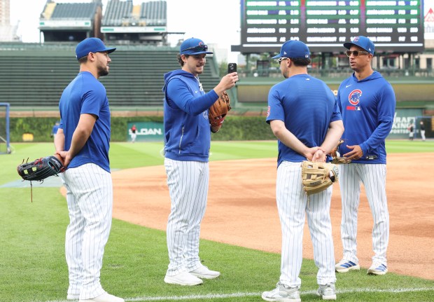 Cubs third baseman Alex Bregman, center right, has his picture taken by hitting development coach Ben Martin before a game against the Marlins at Wrigley Field on Sept. 22, 2026, in Chicago. Bregman was injured in the face by a foul ball on Sept. 20. (John J. Kim/Chicago Tribune)