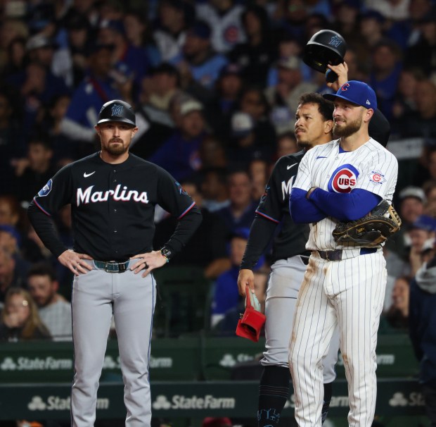 Marlins left fielder Heriberto Hernández takes off his batting helmet as he and Cubs first baseman Michael Busch, right, watch the video review as Hernández is called out on a pickoff from Busch in the third inning at Wrigley Field on Sept. 22, 2026, in Chicago. (John J. Kim/Chicago Tribune)