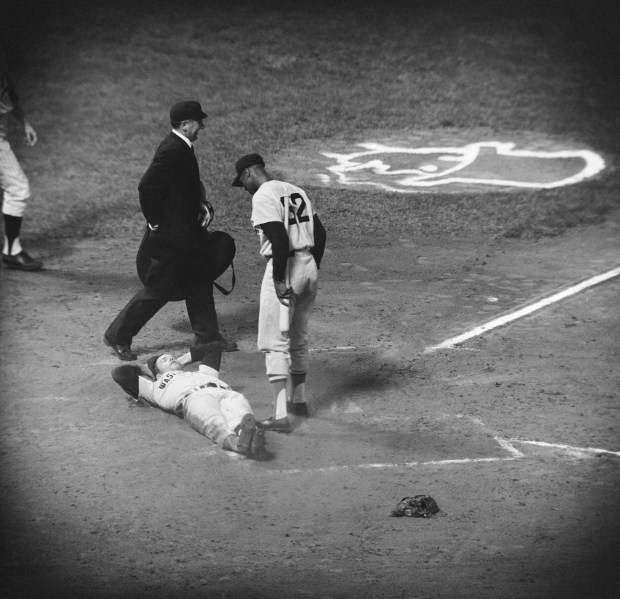 Jim Piersall, centerfielder for the Washington Senators relaxes on the ground after scoring against the Minnesota Twins, June 1, 1962. Others are unidentified. (AP Photo/Gene Herrick)