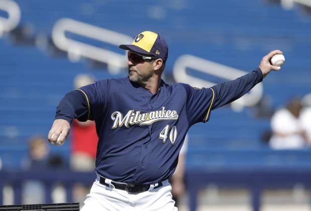 Milwaukee Brewers coach Jason Lane throws during batting practice before a spring training game against the Cleveland Indians, Monday, Feb. 26, 2018, in Maryvale, Ariz. (AP Photo/Carlos Osorio)