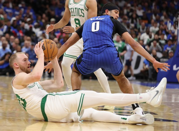 Boston forward Sam Hauser (bottom) tries to pass under Orlando...