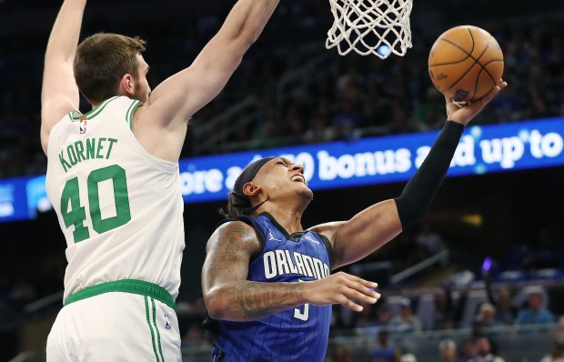 Orlando forward Paolo Banchero (5) scores under Boston center Luke...