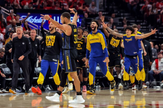 Golden State Warriors players react to Buddy Hield's (7) first quarter buzzer-beater against the Houston Rockets in Game 7 of an NBA basketball first-round playoff series in Houston, Sunday, May 4, 2025. (Carlos Avila Gonzalez/San Francisco Chronicle via AP)